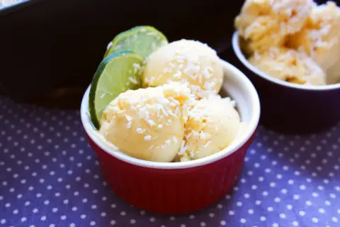 Krämig kvarg glass med kokosflingor och lime i en röd skål. En perfekt sommardessert!