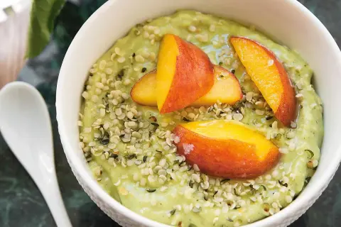 Grön smoothiebowl med avokado, toppad med persikoklyftor och hampafrön. Ett enkelt och gott avokado recept.