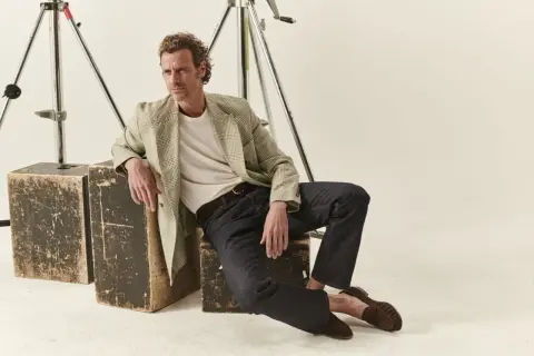 Uomo con un blazer a quadri e jeans scuri, un look fit slim perfetto per ogni occasione.