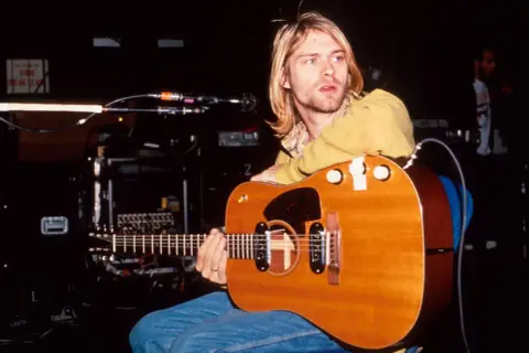Kurt Cobain z gitarą akustyczną, symbol grunge'u i muzyki, która zdefiniowała pokolenie.