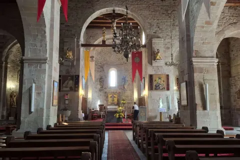 Wnętrze kolegiaty w Kruszwicy. Kamienne mury, łuki, ławki i ołtarz tworzą atmosferę spokoju.