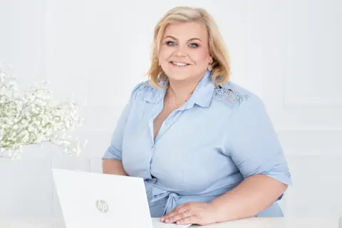 Uśmiechnięta kobieta przy laptopie, gotowa pomóc w znalezieniu pracy w Wielkiej Brytanii.