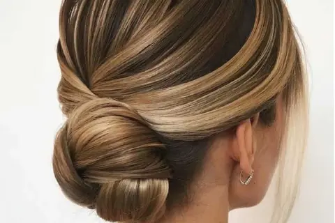 Acconciature capelli medi per cerimonia: un elegante semiraccolto con morbide onde e un chignon basso, perfetto per un look sofisticato.