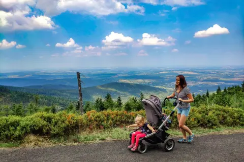 Mama z córką na spacerze, gdzie w góry z wózkiem. Piękny widok na dolinę i chmury.