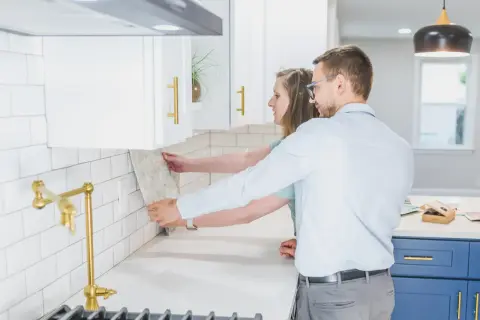 Pareja colocando azulejos en la cocina. ¿Cuánto cuesta alicatar una cocina? Elige el diseño perfecto para tu hogar.