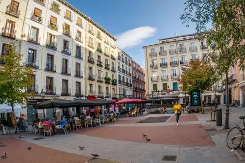 Piazza vivace con caffè all'aperto e persone che passeggiano, un'atmosfera tipica della zona gay di Madrid.