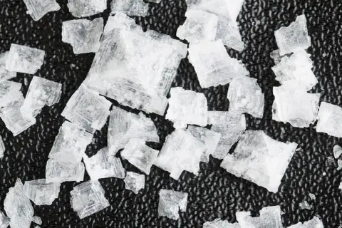 Cristales de sal Maldon, con sus distintivas propiedades y forma piramidal, sobre una superficie oscura.