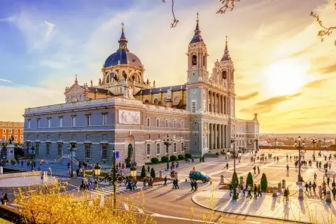 Catedral de la Almudena, uno de los **lugares para conocer en Madrid**, con gente paseando en una tarde soleada.