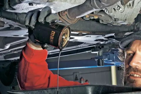 Mechanik wymienia stary olej silnikowy. Pamiętaj, co ile się wymienia olej, by auto służyło latami.