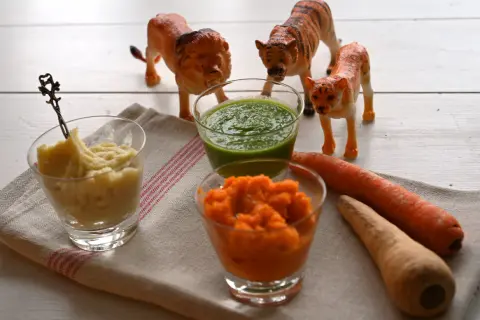 Lekfulla lejon och tigrar vakar över tre skålar med puréer – perfekt för plockmat bebis recept. Morötter och en grön puré ser aptitliga ut.
