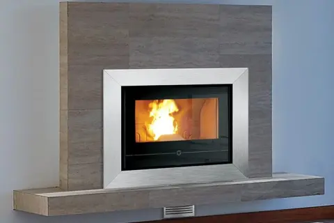 Moderner Kaminofen mit Stahlrahmen und brennendem Feuer. Dieser Kaminofen entspricht der DIN 18895 und ist noch zugelassen.