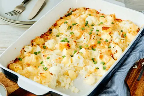 Ein goldbrauner Blumenkohlauflauf mit Käse überbacken und mit Schnittlauch bestreut, bereit zum Servieren.