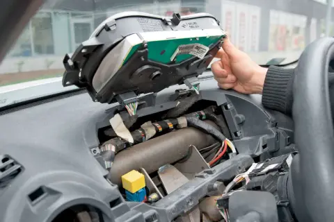 Wymiana żarówek przód w Opel Vivaro. Widok wnętrza zdemontowanego kokpitu, widoczne przewody i elementy deski rozdzielczej.