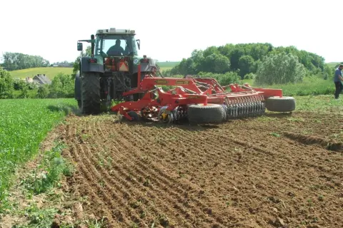Traktor z agregatem uprawowym wykonuje podorywkę na polu.