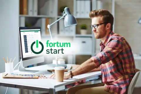 Mężczyzna przy biurku pracuje na komputerze z logo Fortum.