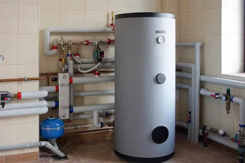 Duży, szary bojler na wodę 200l z licznymi rurami i zaworami, tworzący skomplikowany system grzewczy.