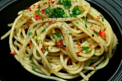 Pyszne spaghetti aglio olio, posypane natką pietruszki i płatkami chili. Idealny przepis na szybki obiad.