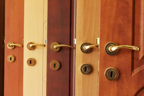 Plusieurs portes en bois aux teintes variées, chacune ornée d'une poignée dorée. L'idée de peindre une porte en bois prend tout son sens devant cette diversité.