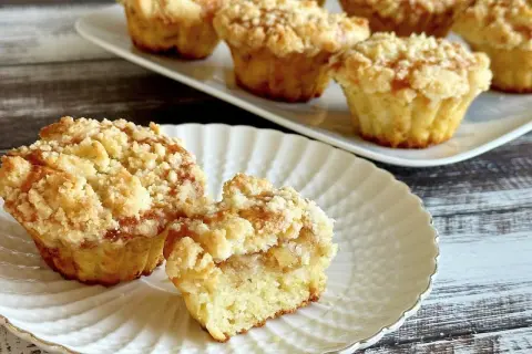 Pyszne muffinki z jabłkami, z kruszonką na wierzchu, prezentowane na białym talerzyku.