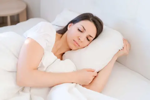 A woman sleeps peacefully, finding comfort and rest. This image illustrates how to sleep with vertigo, suggesting a serene and undisturbed slumber.