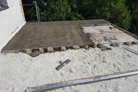 Budowa dachu z wykorzystaniem styrobetonu. Widać świeżo wylany materiał, który czeka na dalsze prace. Kluczowe są odpowiednie proporcje styrobetonu.