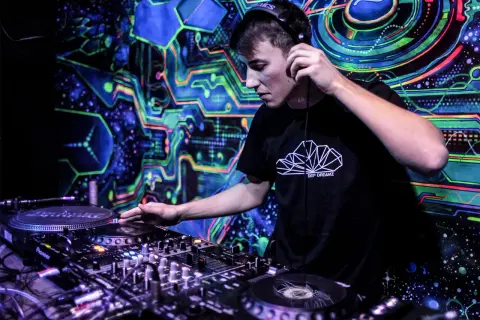 Młody DJ w słuchawkach miksuje muzykę w klubie z psychodelicznym tłem. Chcesz wiedzieć, jak zostać DJ w klubie? Zacznij od tego!