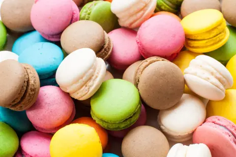 Montón de macarons de colores: rosa, verde, amarillo, azul, blanco y marrón. Estos dulces, de donde son los macarons, son un deleite visual y gustativo.