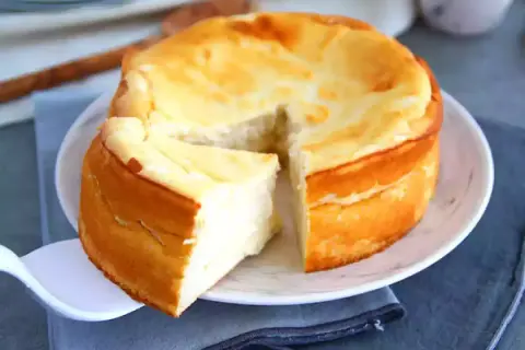 Un délicieux dessert fromage blanc rapide, un gâteau moelleux et doré, une part est déjà servie.