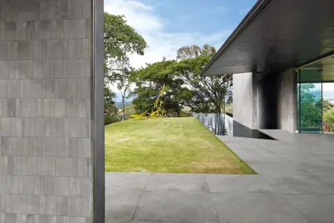 Pareti e pavimenti in gres 2 cm creano un'atmosfera moderna, con piscina a sfioro e scultura gialla in giardino.