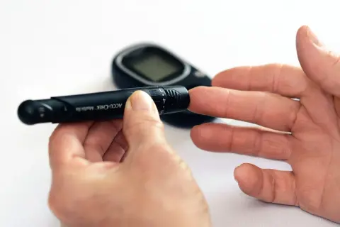 Osoba przygotowuje się do pobrania próbki krwi glukometrem. To ważny krok w monitorowaniu cukrzycy, który może pomóc w uniknięciu bólu i innych dolegliwości, podobnie jak skuteczny lek przeciwbólowy.