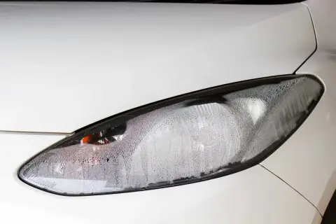 Faros empañados por dentro: una solución para la condensación en el faro de un coche blanco.