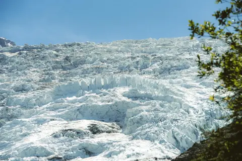 Vaste étendue de glace craquelée et texturée du glacier des Bossons sous un ciel bleu clair.