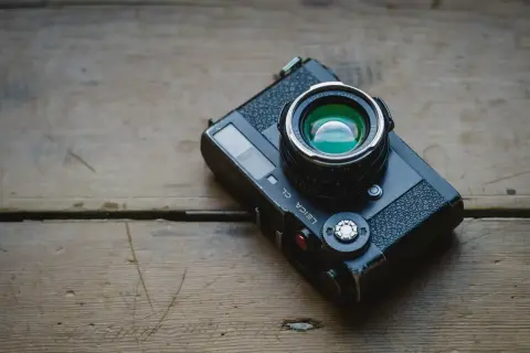 A Leica CL camera with a Nokton Classic lens rests on a weathered wooden surface, ready for a detailed review.