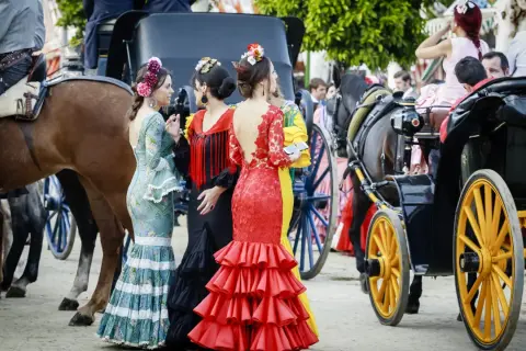 Mujeres con trajes de flamenca y caballos, evocando de donde proviene el flamenco.