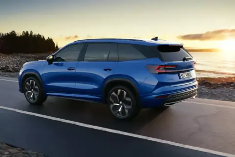Niebieski Skoda Kodiaq jedzie wzdłuż wybrzeża o zachodzie słońca. Poznaj jego imponujące skoda kodiaq wymiary.