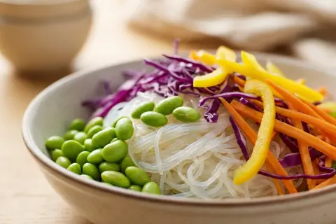 Schüssel mit Glasnudeln, Edamame, Rotkohl, Karotten und gelbem Paprika. Sind Glasnudeln gesund? Ja, sie sind eine leichte und nährstoffreiche Option.