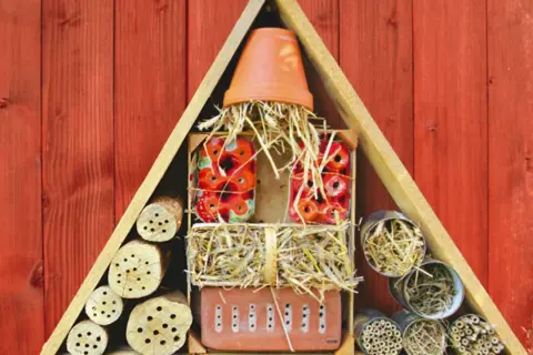 Ein selbstgebautes Insektenhotel aus Holz, Stroh und verschiedenen Materialien bietet Unterschlupf für nützliche Tiere.
