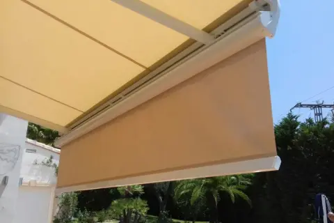 Toldo desplegado, listo para cambiar tela. Sombra agradable en el jardín con palmeras.