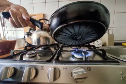 Gotowanie na małym ogniu to jeden ze sposobów, jak obniżyć rachunki za gaz. Patelnia nad płomieniem.