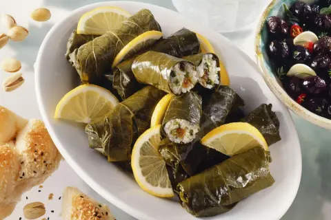Gefüllte Weinblätter, ein köstliches Dolmades Rezept, serviert mit Zitronenspalten und Oliven.