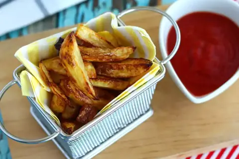 En korg med gyllene pommes frites, redo att doppas i ketchup. Perfekt för en mysig kväll.
