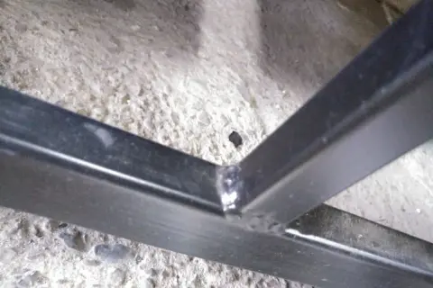 Solidne spawanie profili ocynkowanych, tworzące mocne połączenie konstrukcji metalowej na betonowym podłożu.