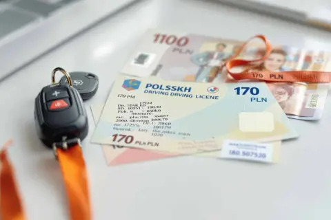 Kluczyki do samochodu i polskie prawo jazdy na samochód leżą obok banknotów.