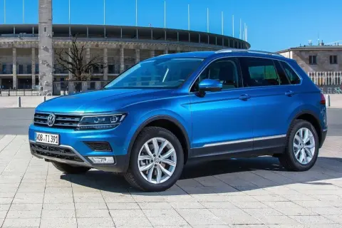Niebieski VW Tiguan Allspace parkuje przed stadionem.