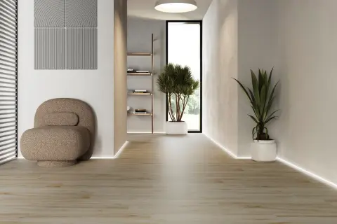 Ljus hall med klinker som ser ut som trägolv. En unik fåtölj och gröna växter skapar en inbjudande atmosfär.