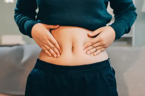 Mani che stringono la pancia, che nonostante sia magra, appare gonfia e dura.