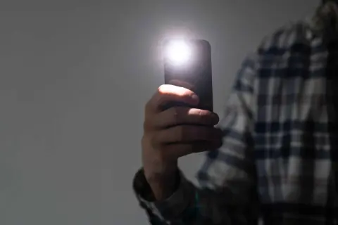 Dłoń trzyma smartfon Samsung, którego lampa błyskowa świeci. Zastanawiasz się, dlaczego nie działa lampa błyskowa w aparacie Samsung?