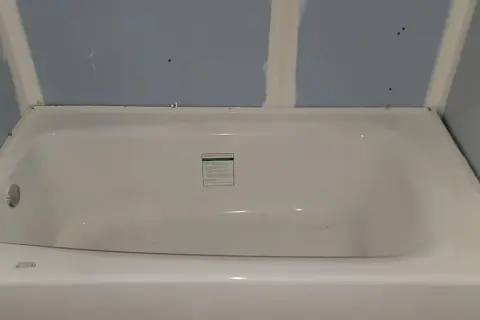 Installing cement board around a tub is underway. The tub is in place, and the blue drywall is being prepped for the next steps.