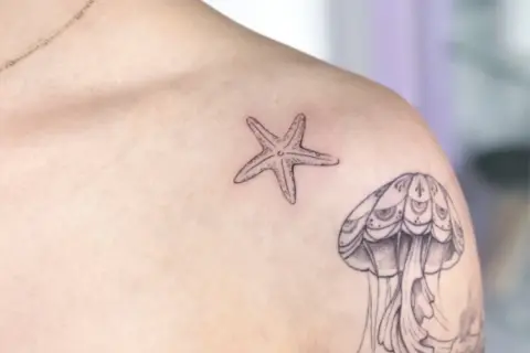 Kleines Seestern-Tattoo auf der Brust, neben einer Qualle.