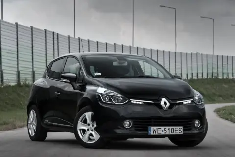 Czarny Renault Clio 4 z 2013 roku na drodze, z barierą dźwiękochłonną w tle.